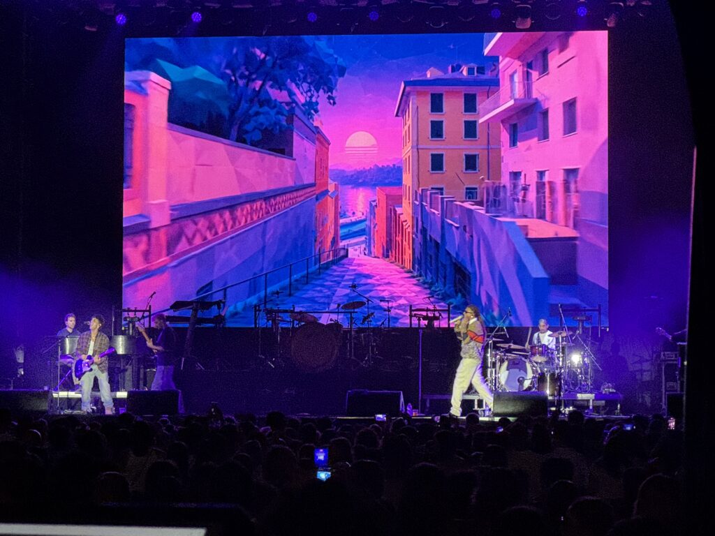 Sayf e la band sul palco con visual rosa e blu sul ledwall